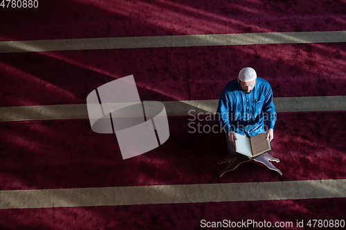 Image of muslim man praying Allah alone inside the mosque and reading islamic holly book