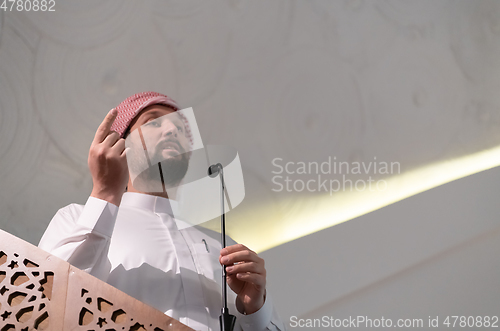 Image of Muslims young arabic Imam has a speech on friday afternoon prayer in mosque.