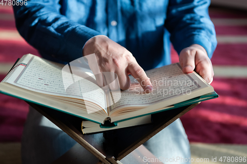 Image of muslim man praying Allah alone inside the mosque and reading islamic holly book