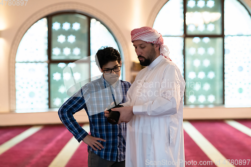 Image of the father explains to his son how to use the camera in mosque