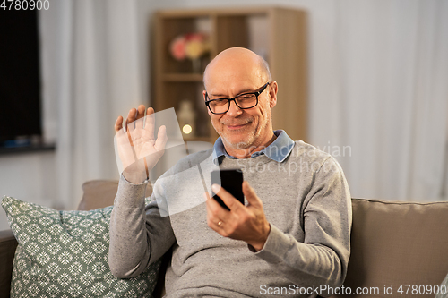 Image of old man with smartphone having video call at home