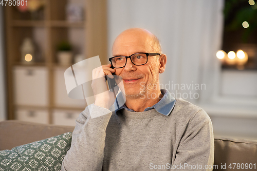 Image of happy senior man calling on smartphone at home