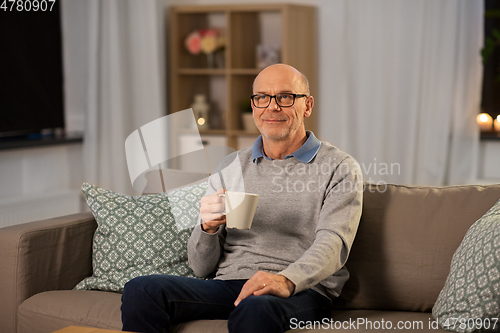 Image of happy senior man with cup of tea at home