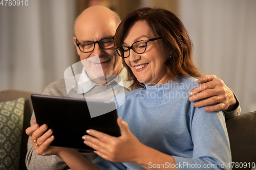 Image of happy senior couple with tablet pc at home