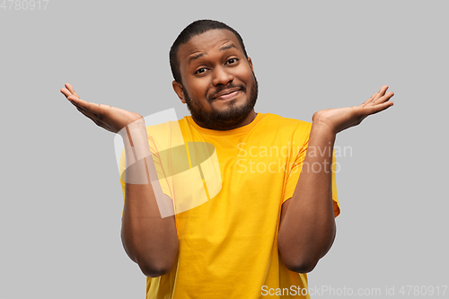 Image of african american man in yellow t-shirt shrugging