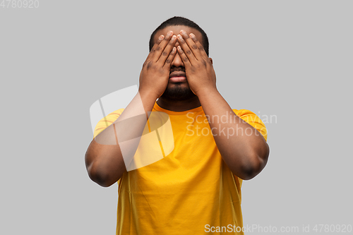 Image of african american man closing his eyes by hands