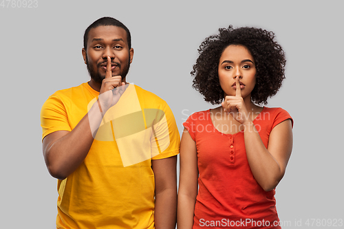 Image of happy african american couple making hush gesture