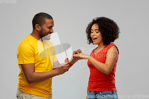 Image of african american man giving woman engagement ring