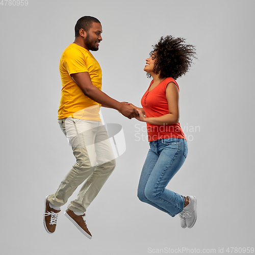 Image of happy african american couple jumping in air