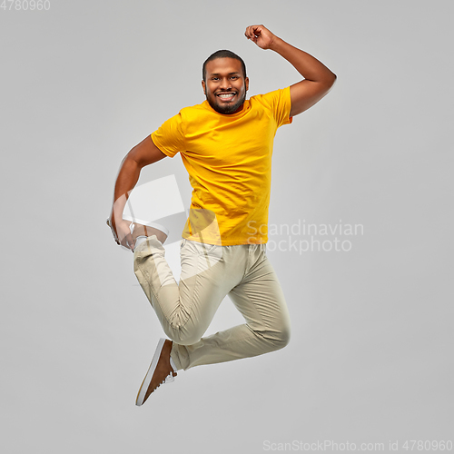 Image of smiling young african american man jumping in air