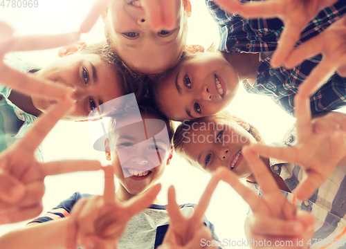 Image of group of happy children showing v sign in circle