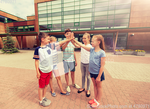 Image of group of children making high five at school yard