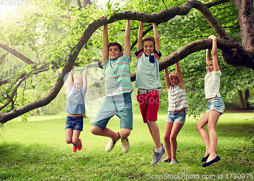 Image of happy kids hanging on tree in summer park