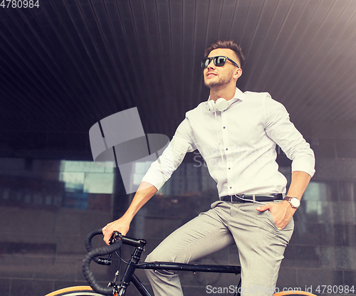 Image of man with bicycle and headphones on city street