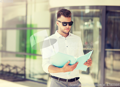 Image of young man with business file on city street