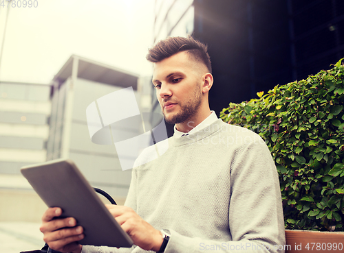 Image of man with tablet pc sitting on city street bench