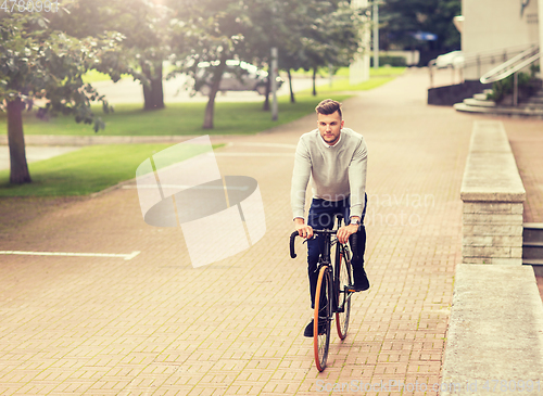 Image of young man riding bicycle on city street