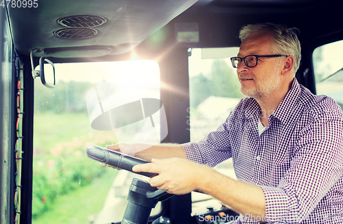 Image of senior man driving tractor at farm