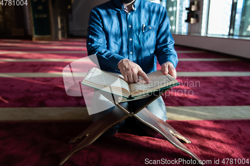 Image of muslim man praying Allah alone inside the mosque and reading islamic holly book