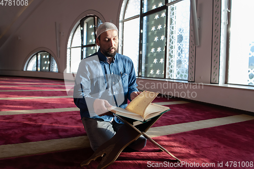 Image of muslim man praying Allah alone inside the mosque and reading islamic holly book