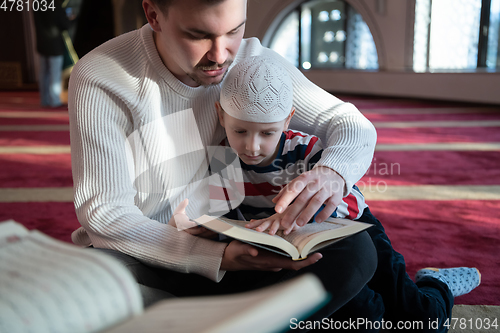 Image of  father and son in mosque praying and reading holly book quran together islamic education concept