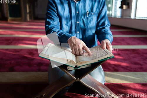 Image of muslim man praying Allah alone inside the mosque and reading islamic holly book