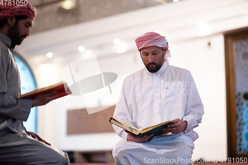 Image of two muslim people in mosque reading quran together concept of islamic education