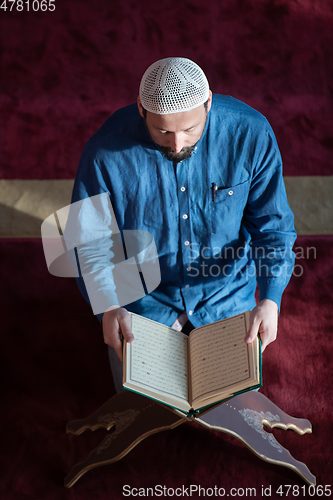 Image of muslim man praying Allah alone inside the mosque and reading islamic holly book
