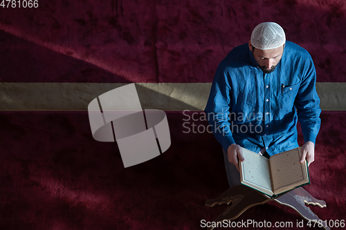 Image of muslim man praying Allah alone inside the mosque and reading islamic holly book