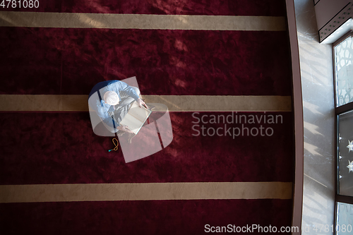 Image of muslim man praying Allah alone inside the mosque and reading islamic holly book