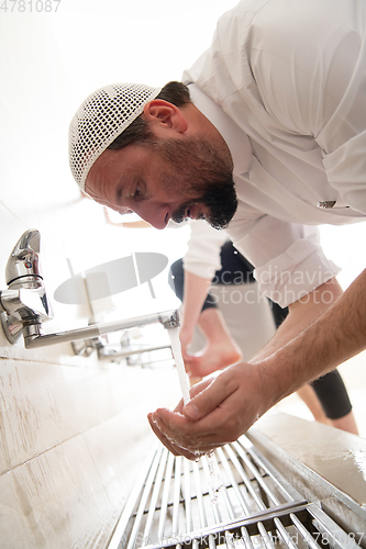 Image of a group of Muslims take ablution for prayer. Islamic religious rite