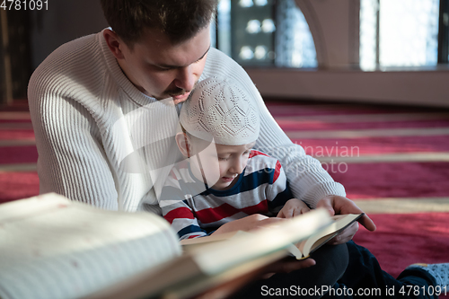 Image of  father and son in mosque praying and reading holly book quran together islamic education concept