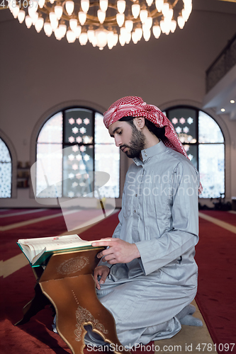 Image of muslim man praying Allah alone inside the mosque and reading islamic holly book