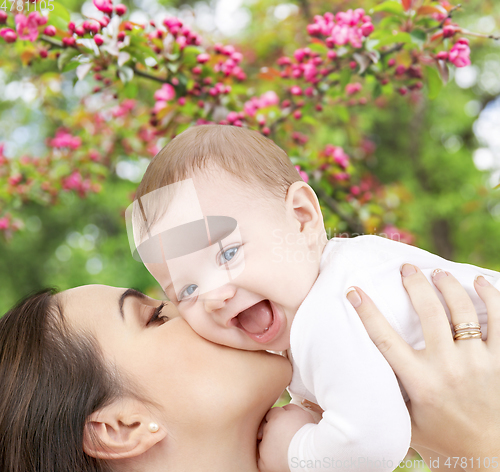 Image of close up of mother kissing baby over garden