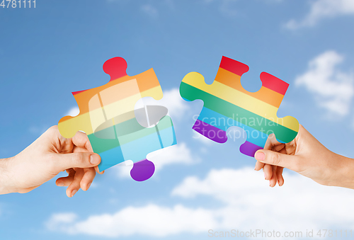 Image of hands matching puzzle pieces with gay flag colors