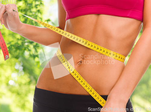 Image of close up of woman measuring her waist with tape