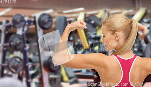 Image of young sporty woman showing her biceps in gym