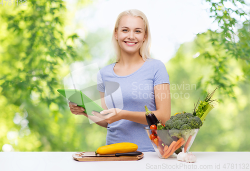 Image of smiling young woman with tablet pc cooking