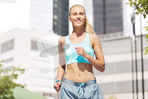 Image of smiling young woman running at city