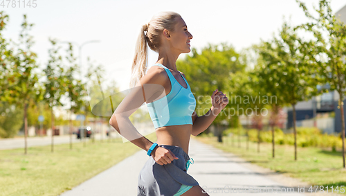 Image of smiling young woman running outdoors