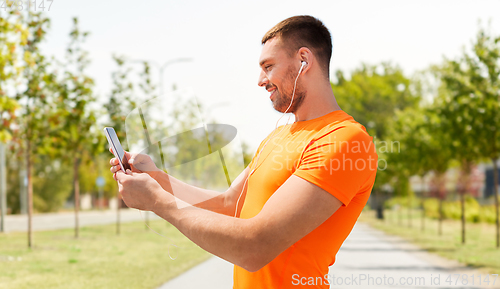 Image of smiling young man with smartphone and earphones