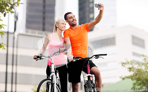 Image of couple with bicycles taking selfie by smartphone