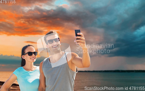 Image of couple taking selfie by smartphone on beach