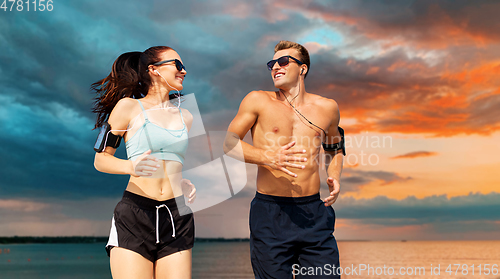 Image of couple with phones and arm bands running over sea