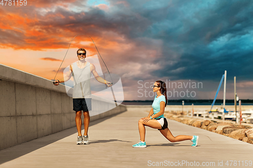 Image of happy couple warming up on pier before training