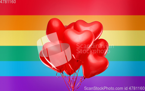 Image of red heart shaped helium balloons over rainbow flag