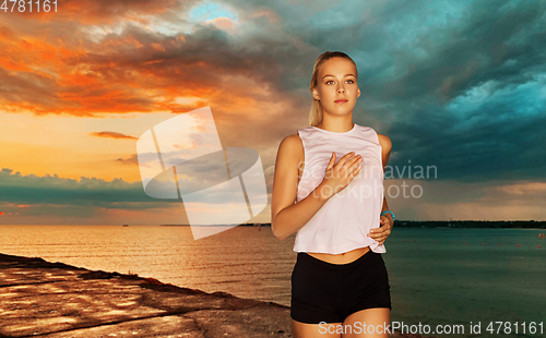 Image of happy young woman running along sea pier