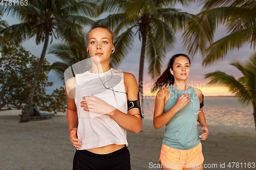 Image of young women with earphones and smartphones running