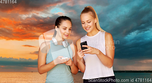 Image of women or female friends with smartphones over sea