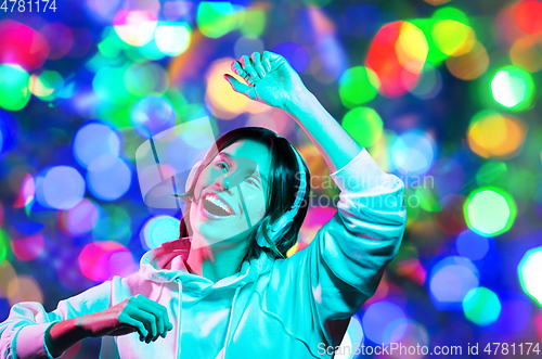 Image of woman in headphones dancing over night lights